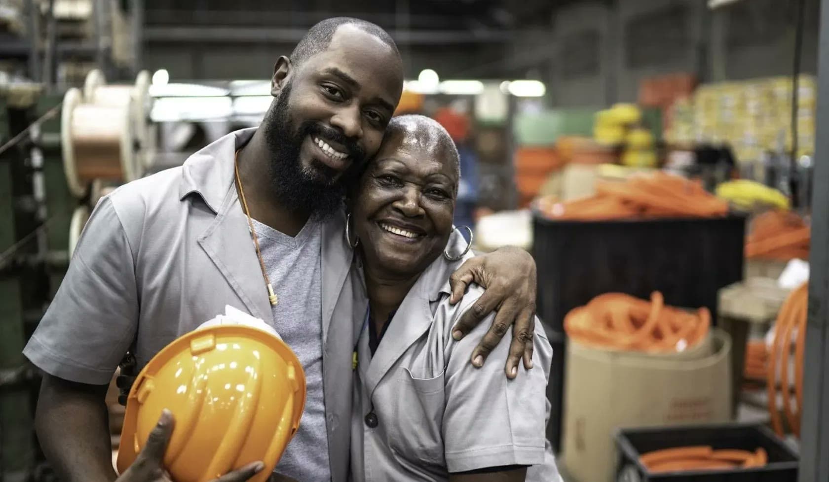 Two factory workers smiling on the production floor