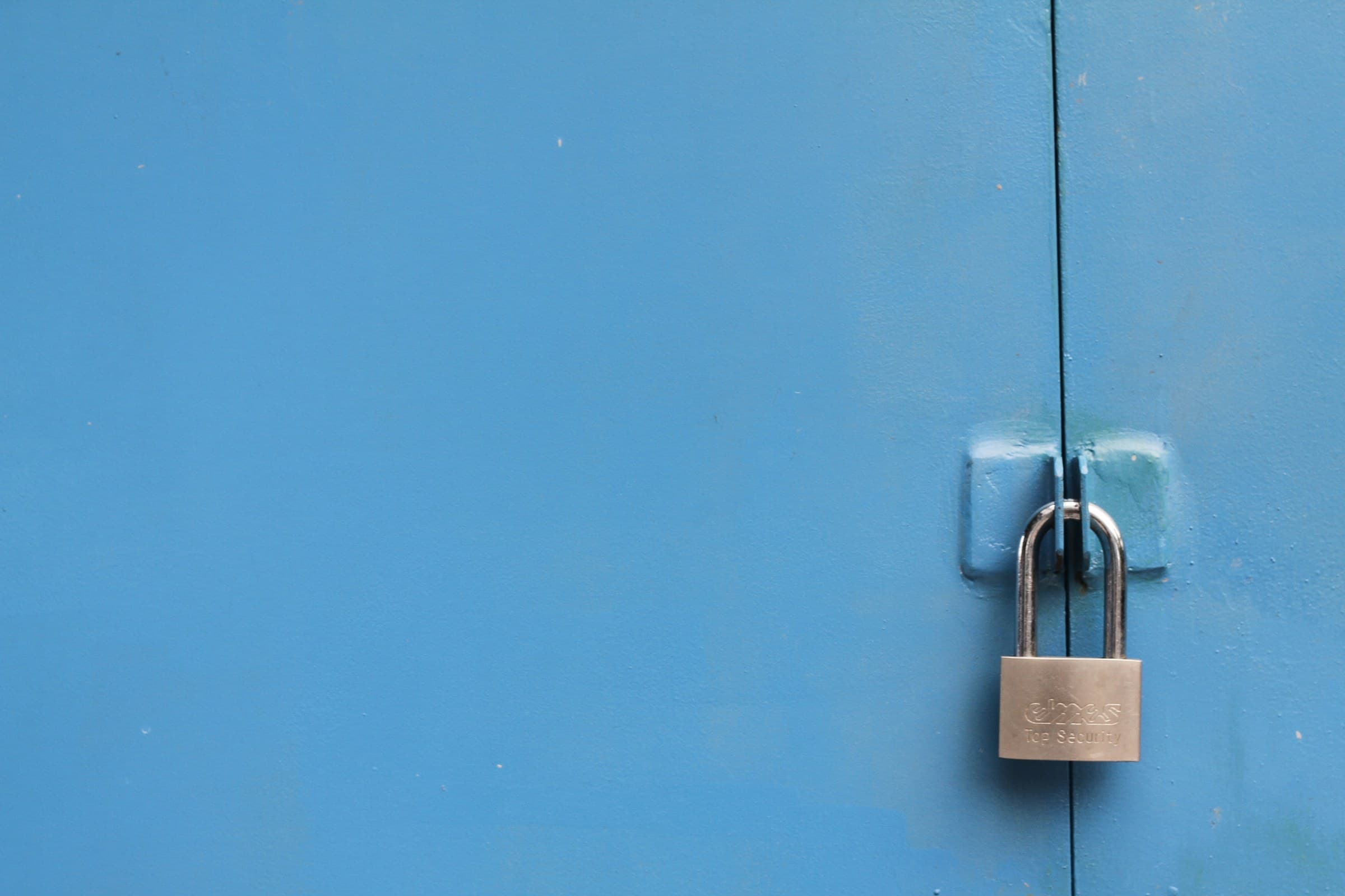 A padlock securing a blue metal door